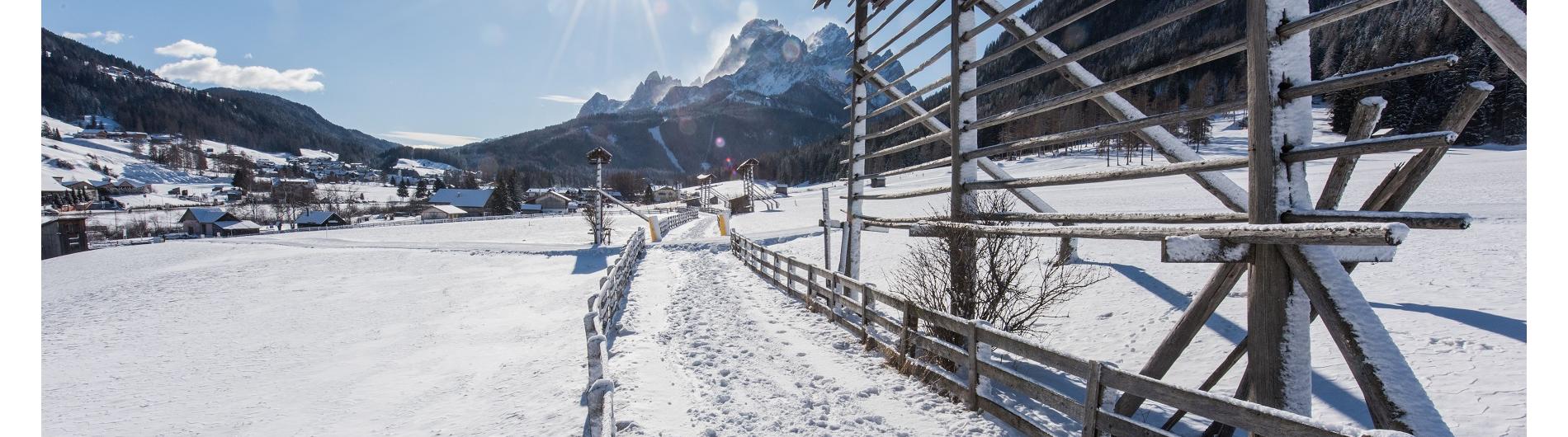 Winterwanderweg mit Sonneneinstrahlung und Bergblick im Dorf