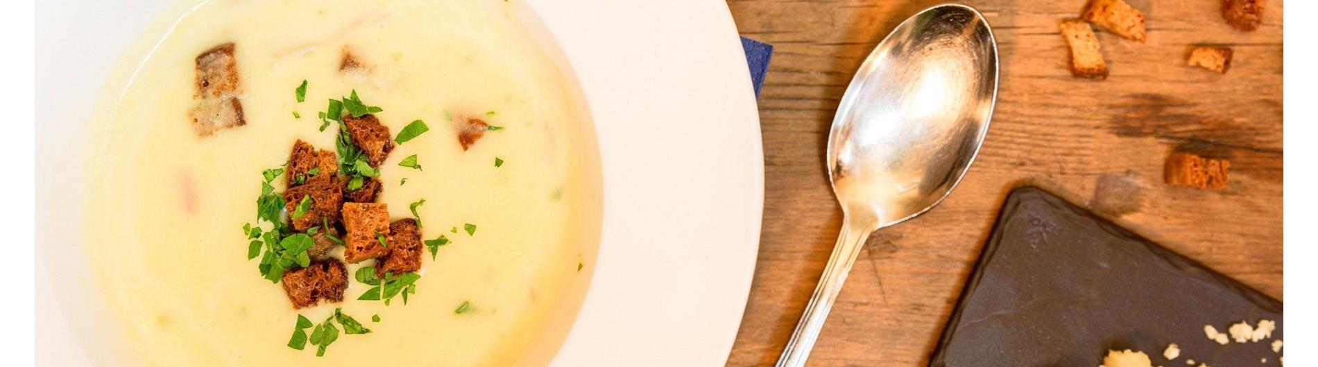 Piatto di zuppa con crostini di pane e cucchiaio da zuppa