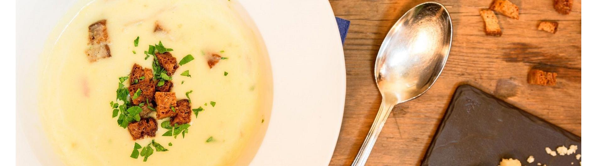 Suppenteller mit Brotcoutons und Suppenlöffel