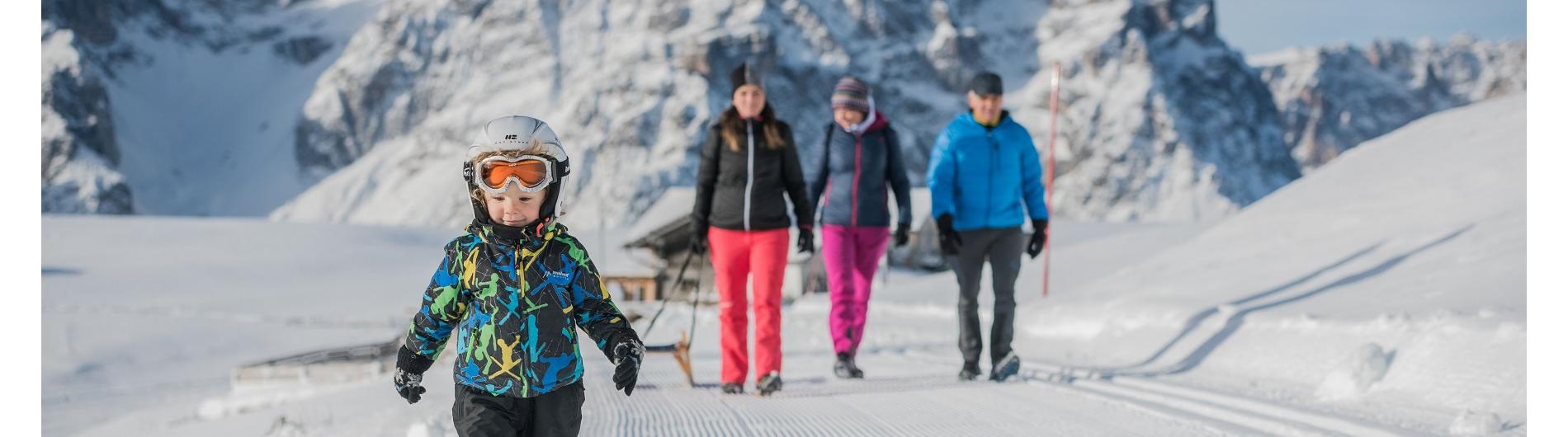 Family with child walking with a sled on the sledding track