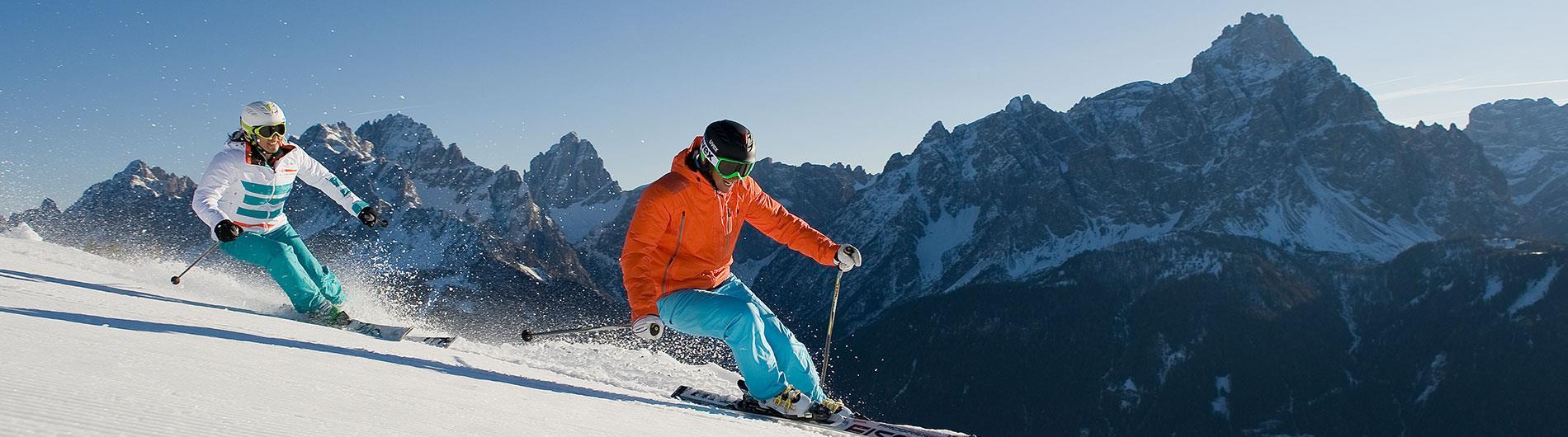 Zwei Skifahrer mit Bergkulisse im Hintergrund