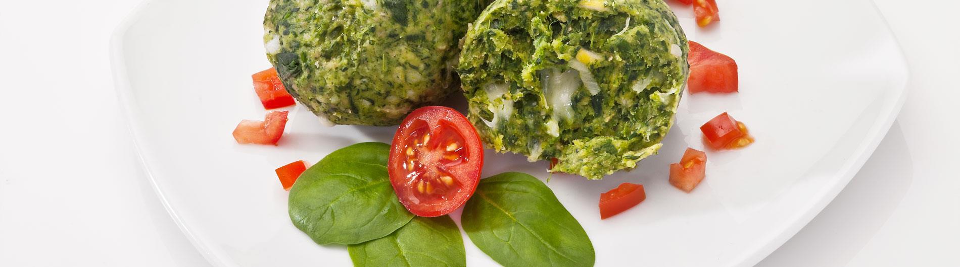 Canederli di spinaci serviti con basilico e pomodoro