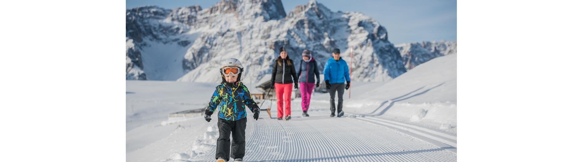 Family with child walking with a sled on the sledding track