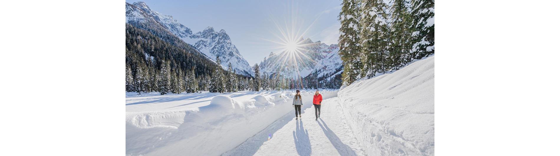 Winter hiking in the Val Fiscalina Valley with a view of the Cima Dodici Mountain as the sun breaks through