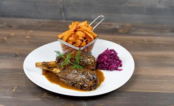 Rehhaxe serviert mit Blaukraut und Süßkartoffelpommes