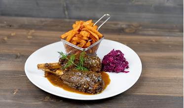 Rehhaxe serviert mit Blaukraut und Süßkartoffelpommes